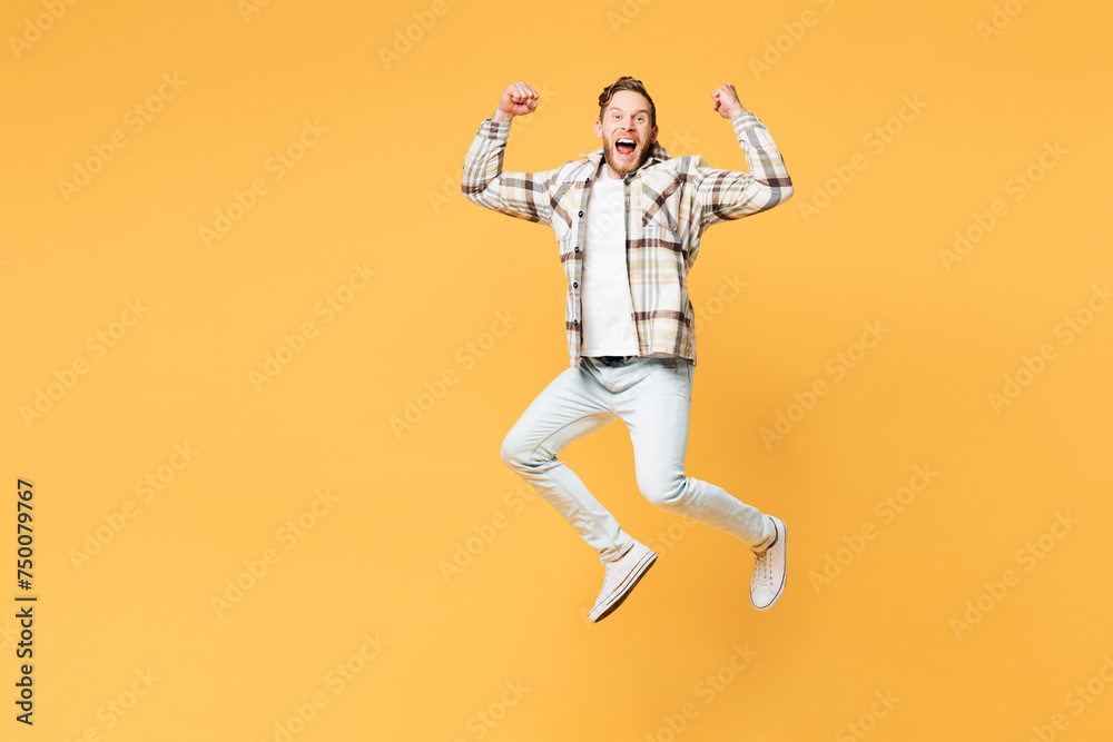 Full body overjoyed happy young Caucasian man he wear brown shirt casual clothes jump high do winner gesture look camera isolated on plain yellow orange background studio portrait. Lifestyle concept.