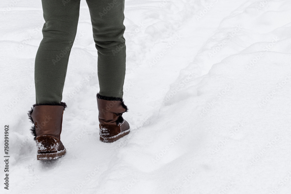 woman in solid shoes walks along a snowy path. woman in solid shoes walks along a snowy path.