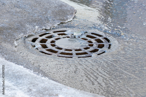Melt water from snow and ice flows into the storm drain manhole