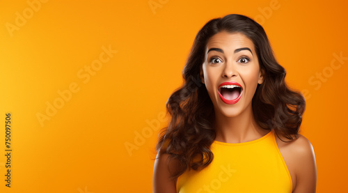 Portrait d'une belle femme brune surprise, étonnée, sur fond orange, image avec espace pour texte.