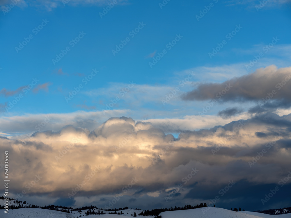 Cloudscape over a snow filed with forested hills Cloudscape over a snow filed with forested hills