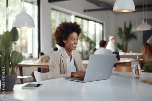 Smiling professional at laptop, modern workspace, business casual, bright office, productivity, positive work environment