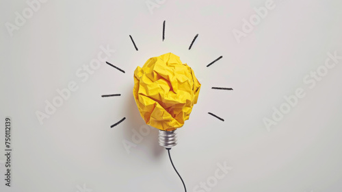 A crumpled piece of yellow paper forms the shape of a lightbulb against a white background, symbolizing a bright idea or creative concept.