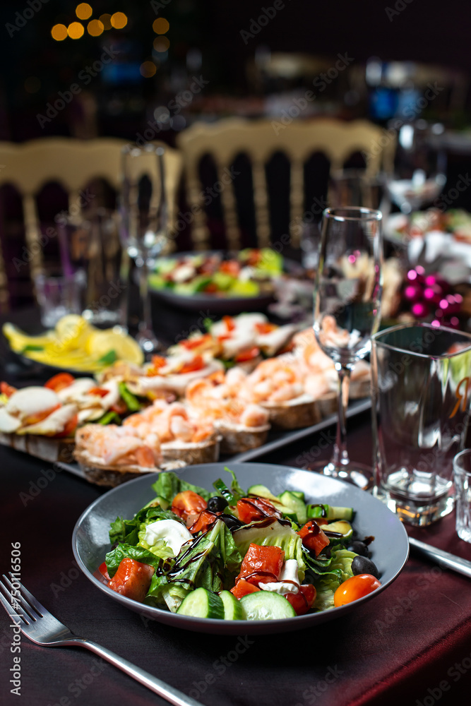 Dinner Greek salad of fresh cucumber, tomato, sweet pepper, lettuce,feta cheese, olives and balsamic vinegar with bruschetta on table.