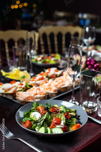 Obraz na płótnie Dinner Greek salad of fresh cucumber, tomato, sweet pepper, lettuce,feta cheese, olives and balsamic vinegar with bruschetta on table. w salonie