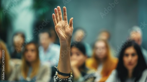 A group of individuals seated indoors, raising their hands in unison