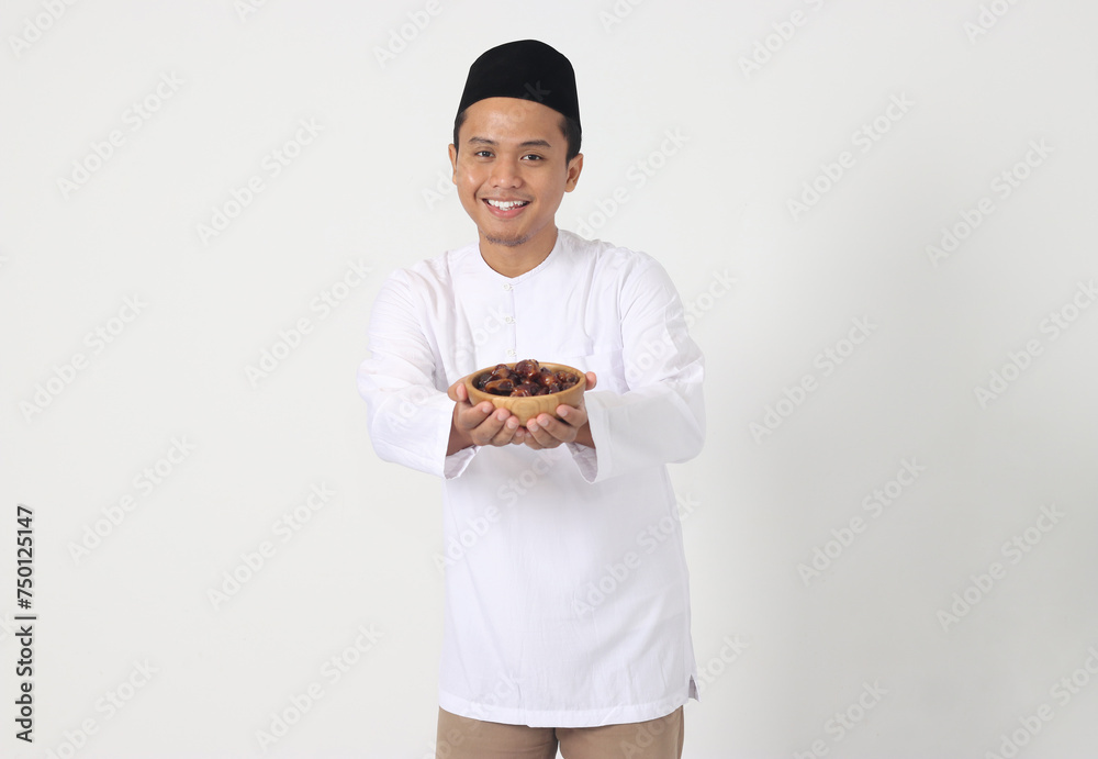 Portrait of excited Asian muslim man eating date fruit during sahur or breaking the fast. Culture and tradition on Ramadan month. Isolated image on white background Portrait of excited Asian muslim man eating date fruit during sahur or breaking the fast. Culture and tradition on Ramadan month. Isolated image on white background