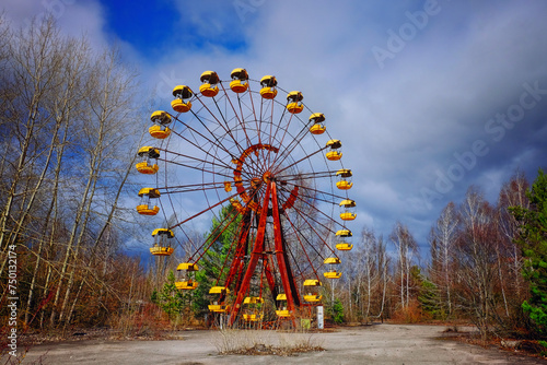 The image shows an unused, rusty Ferris wheel with yellow cabins.