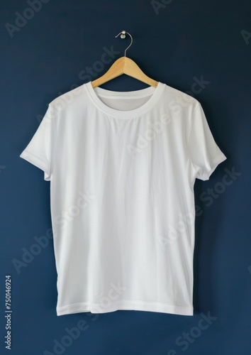 White t-shirt on wooden hanger on blue wall background.