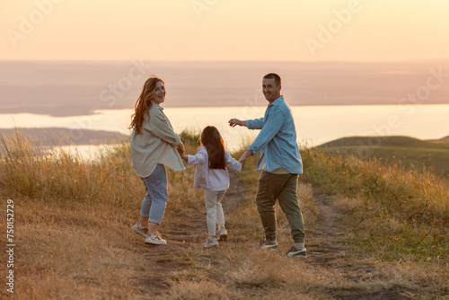 Happy family at sunset. Father, mother and daughter have fun and play in nature. Summer concept. People spend time outdoor in summer