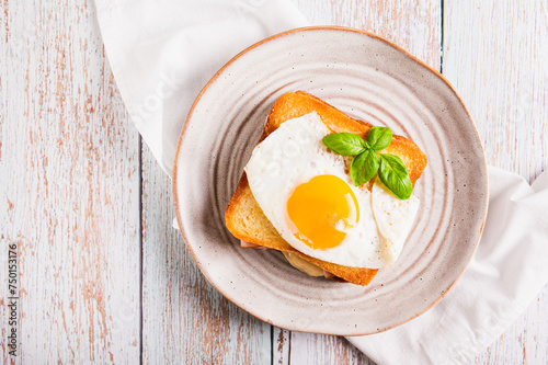 Close up of croque madame sandwich with ham, cheese and egg on a plate on the table top view photo