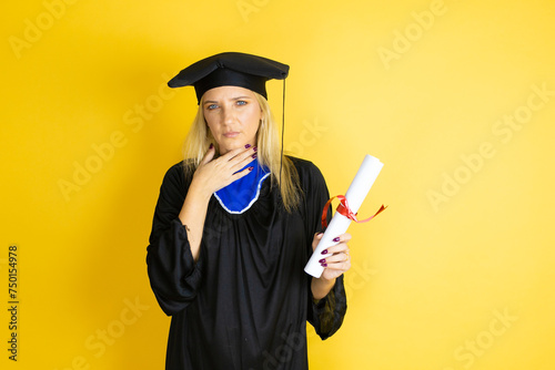 Beautiful blonde young woman wearing graduation cap and ceremony robe touching painful neck, sore throat for flu, clod and infection photo
