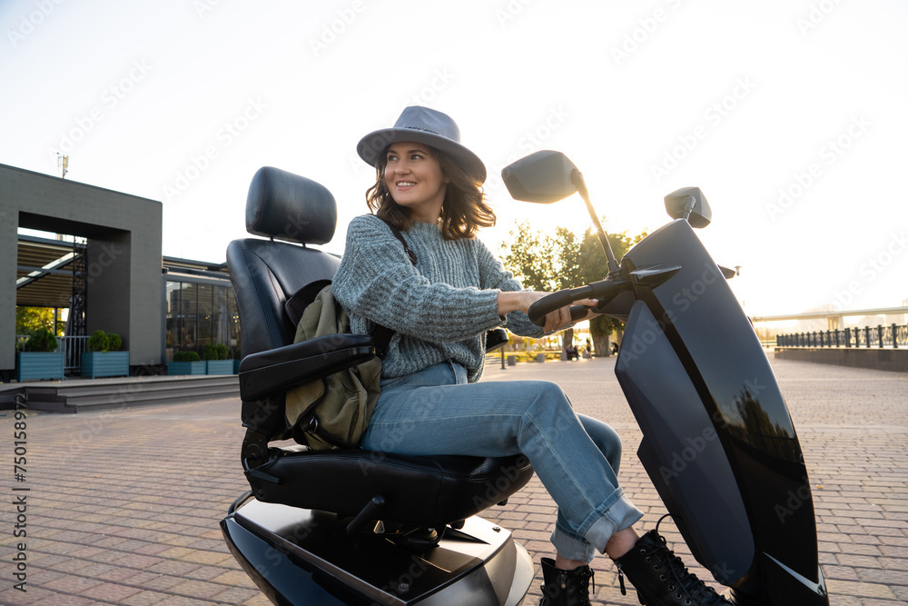 Obraz premium Woman tourist riding a four wheel mobility electric scooter on a city street