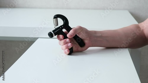 Physical therapy for the arm using an expander, a male hand close-up on a white background squeezes the expander. Recovery after a fracture.