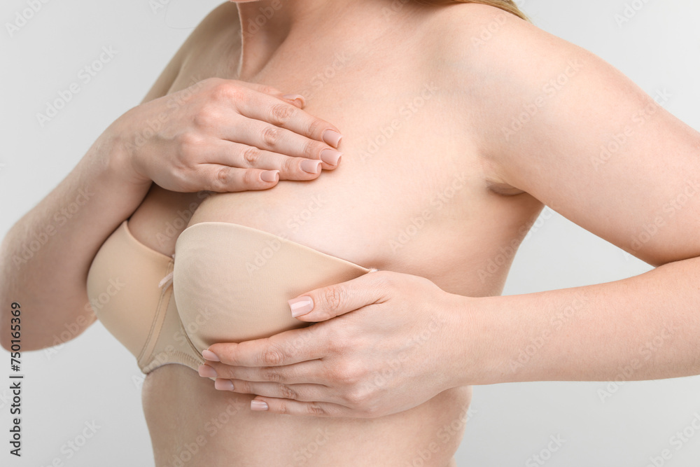 Mammology. Young woman doing breast self-examination on light grey background, closeup