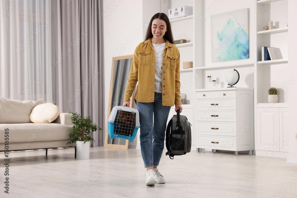 Travel with pet. Smiling woman holding carrier with dog and backpack at home Travel with pet. Smiling woman holding carrier with dog and backpack at home