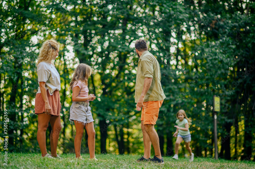 Fototapeta premium Parents and big sister are waiting for a girl who is running to them in nature.