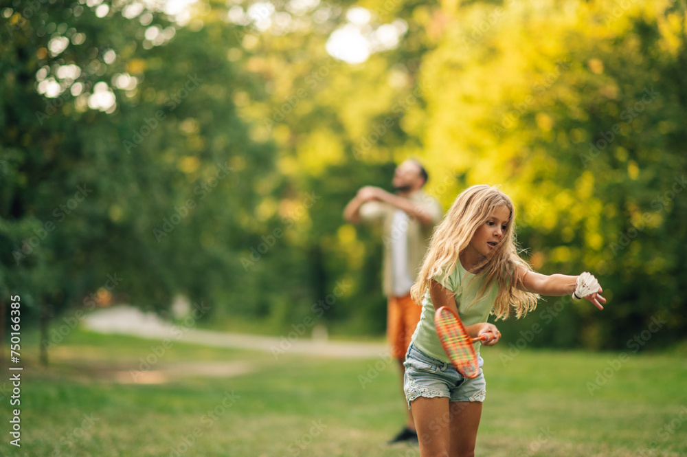 A girl is holding racquet and playing badminton in nature.