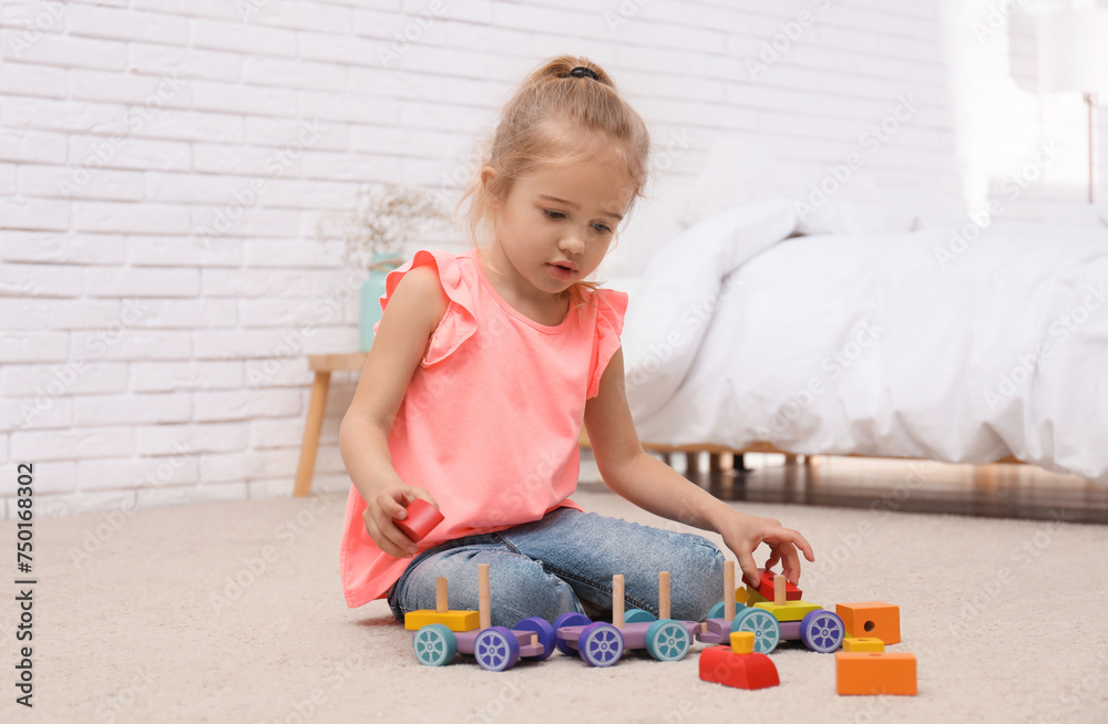 Cute child playing with wooden train on floor at home Cute child playing with wooden train on floor at home