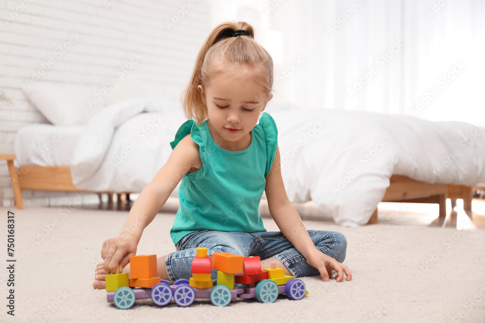 Cute child playing with wooden train on floor at home Cute child playing with wooden train on floor at home