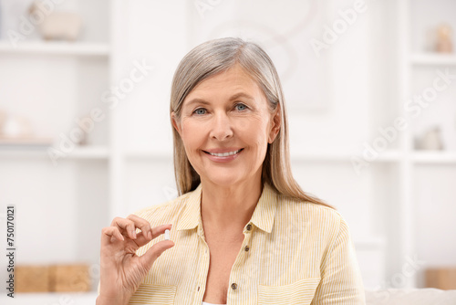 Menopause, hormone replacement therapy. Happy woman holding pill at home
