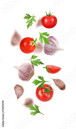 Fresh garlic, tomato and parsley falling on white background