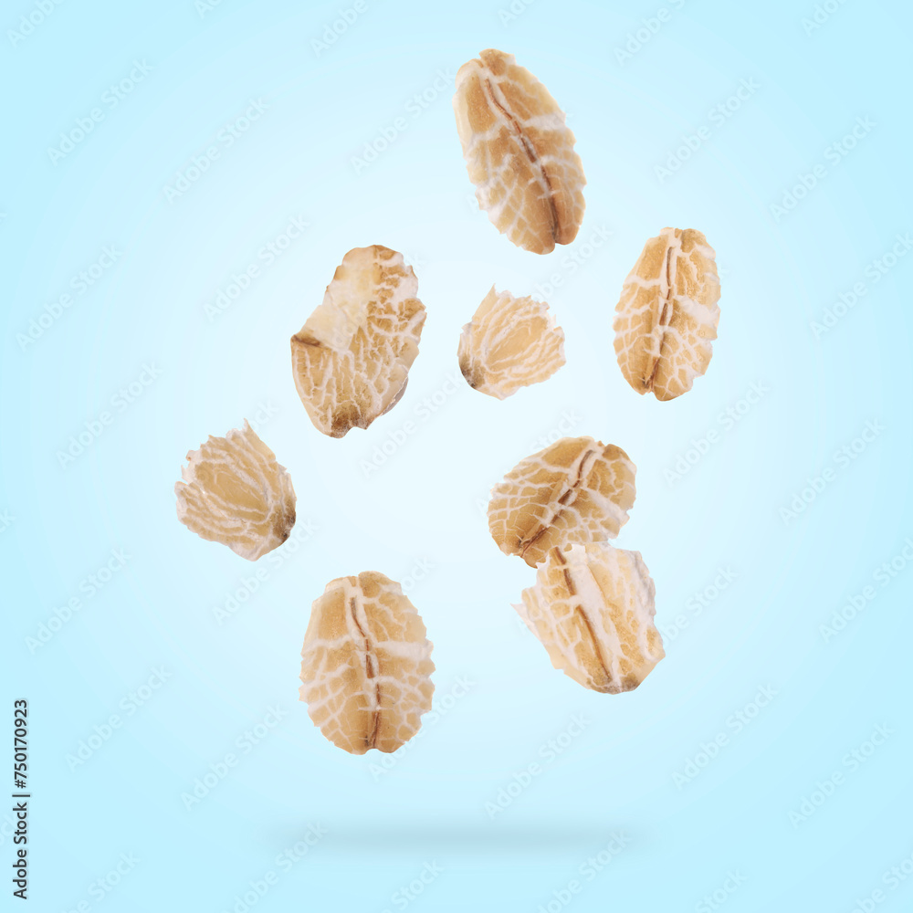 Rolled oat flakes falling on light blue background