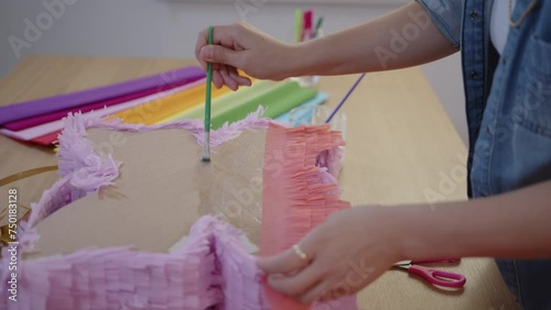 Hispanic woman making colorful pinata in small business studio