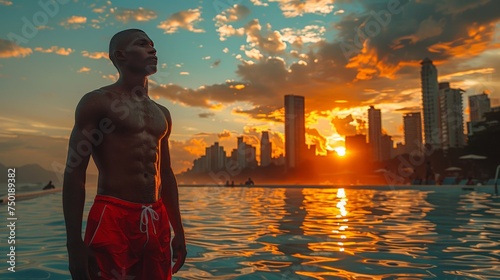 a lifeguard in red shorts, taking a momentary pause to gaze at the city skyline
