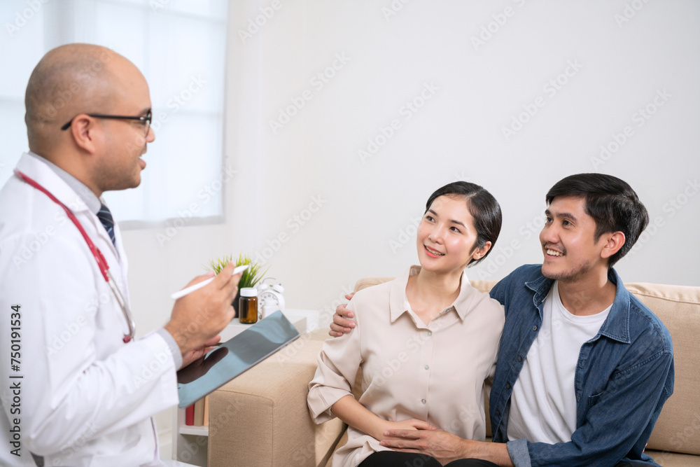 Obraz premium A dark tanned male doctor in a white medical suit discusses a woman's pregnancy. A male doctor opens an iPad showing pregnancy information and recommending dietary supplements and fertility care.