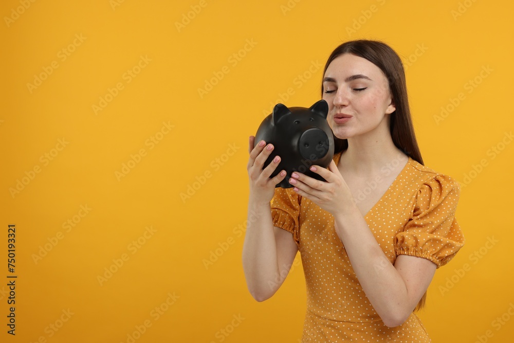 Woman with piggy bank on orange background, space for text