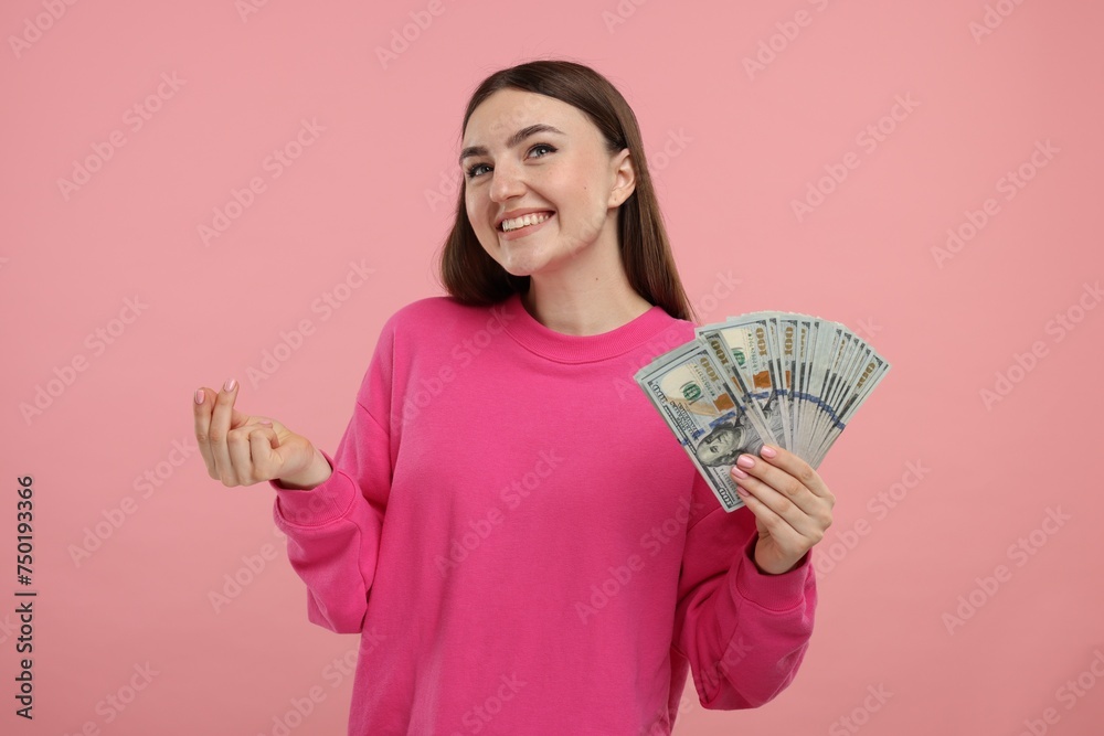 Happy woman with dollar banknotes showing money gesture on pink background Happy woman with dollar banknotes showing money gesture on pink background