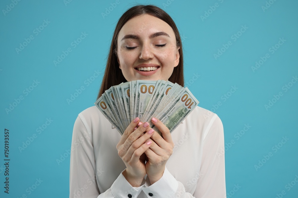 Happy woman with dollar banknotes on light blue background Happy woman with dollar banknotes on light blue background