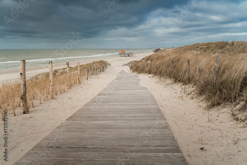 Lifeguard station at beach seen from the dunes with a wooden boardwalk to the beach