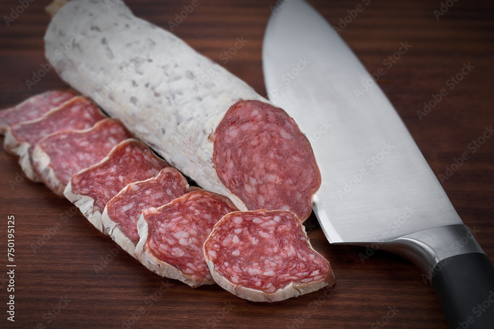 traditional Spanish salami fuet sausage or dry sausage cut in slices in a kitchen table. traditional Spanish salami fuet sausage or dry sausage cut in slices in a kitchen table.