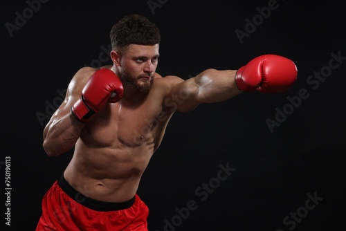 Man in boxing gloves fighting on black background. Space for text © New Africa