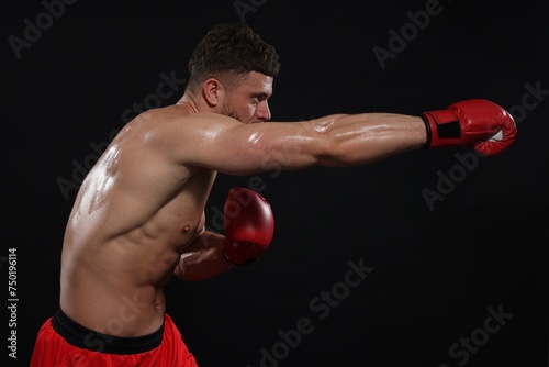 Man in boxing gloves fighting on black background