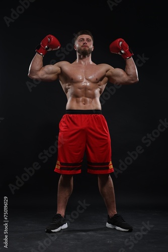 Man in boxing gloves celebrating victory on black background, low angle view © New Africa