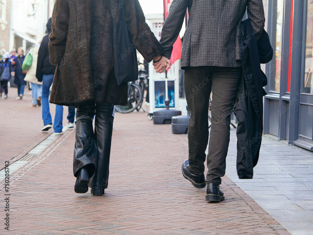 A couple holding hands While Walking Down a a City Street A couple holding hands While Walking Down a a City Street
