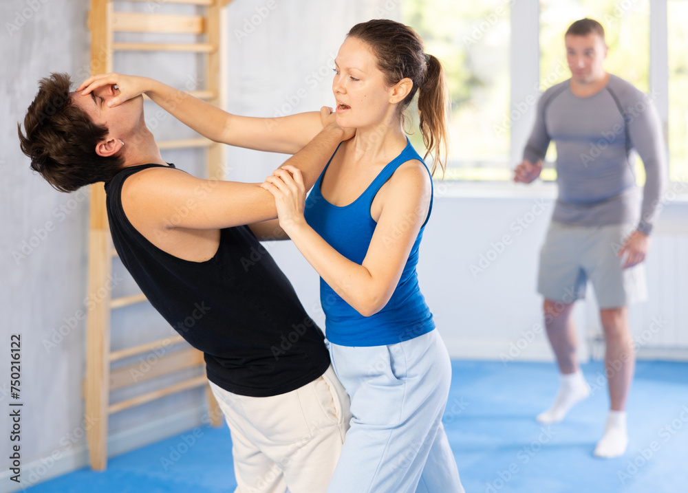 Guy and woman in sparring practice technique of applying painful blows to jaw and groin to neutralize enemy. Class self-defense training in presence of experienced instructor