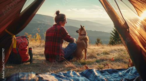 A traveler is relaxing with breathtaking view with golden retriever dog in camping tent on their trip.