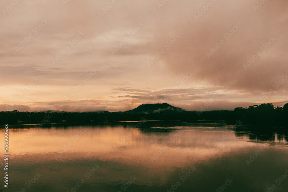 Sunset over the Vaupes River in the Amazon jungle next to a hill.