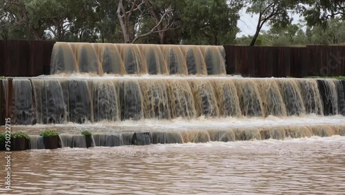 A golden, patterned flow of water falling in three steps over Allan Tannock weir, a water supply dam for Cunnamulla, a town in outback Queensland, Australia, in an unusual time of surplus water. photo