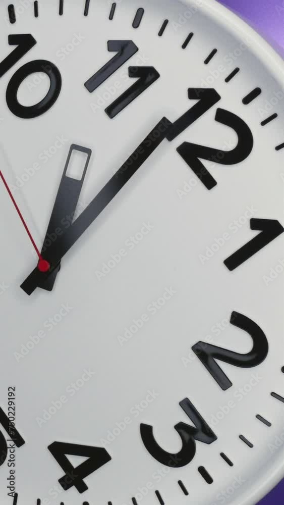 A White Wall Clock On Purple Background With A Time Of 11.00 Am Or Pm. A Black Hands and Red Second Hand Of The Clock. Timelapse. Vertical. A White Wall Clock On Purple Background With A Time Of 11.00 Am Or Pm. A Black Hands and Red Second Hand Of The Clock. Timelapse. Vertical.