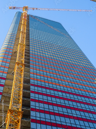 View of the construction of a skyscraper from the bottom up. The crane is attached to a tall building. Construction industry.