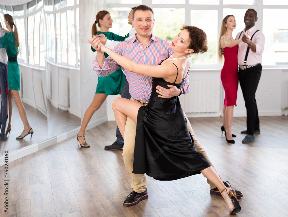 Obraz premium Active middle-aged lady training waltz in pair with man in dance-hall during dancing classes