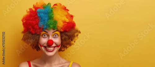 A woman with a clown wig and red nose is smiling at the camera