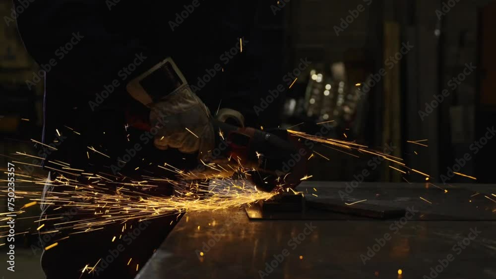 Closeup scene of unrecognisable person using emery to cut metal. Dark scene of hands working on metal Closeup scene of unrecognisable person using emery to cut metal. Dark scene of hands working on metal