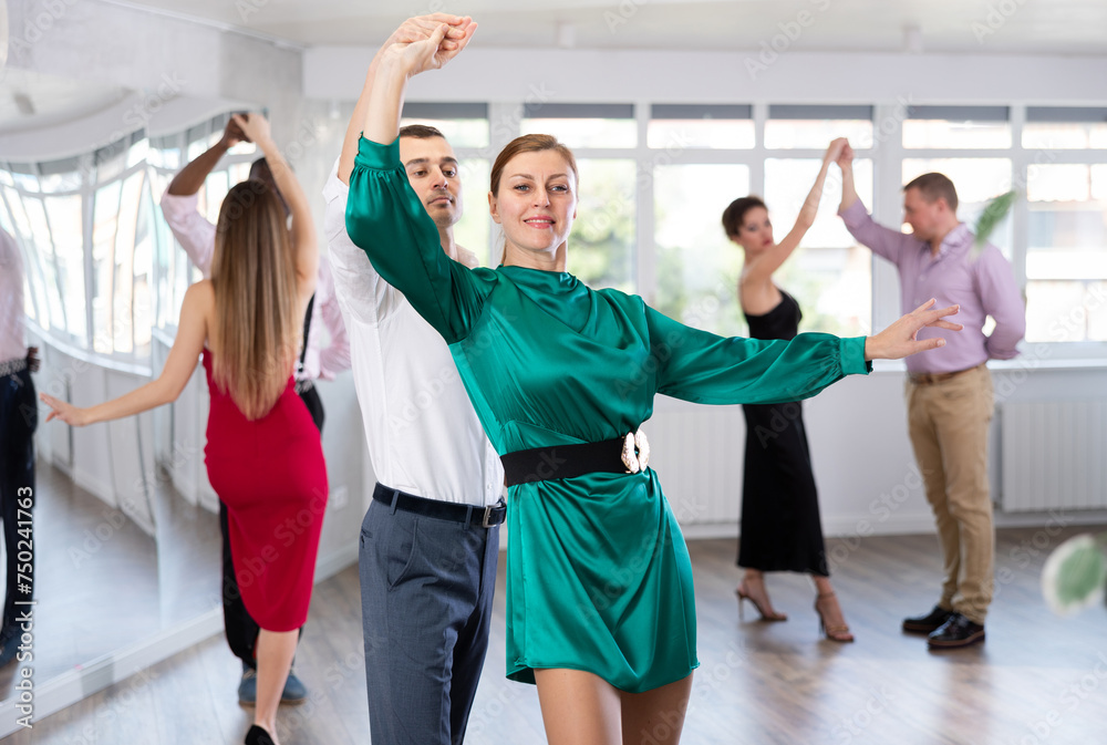 Fototapeta premium Energy man and woman are dancing classic version of waltz in couple during lesson at studio. Leisure activities and physical activity for positive people.