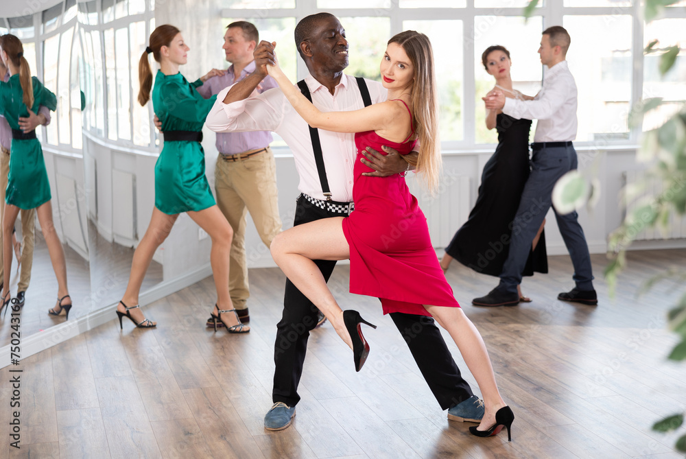 Dance training in group - men and women of different nationalities and different ages dance tango or bachata in a dance studio